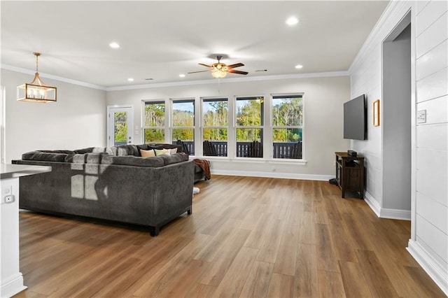 living room featuring recessed lighting, crown molding, wood finished floors, and ceiling fan with notable chandelier