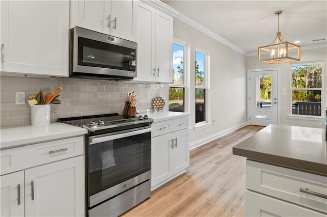 kitchen featuring ornamental molding, light wood-type flooring, stainless steel appliances, backsplash, and a notable chandelier