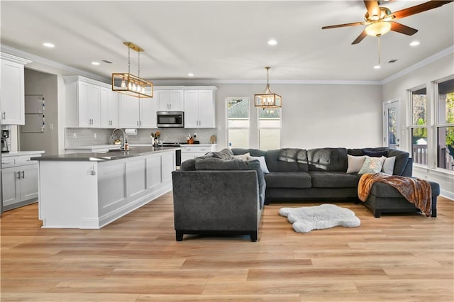 living room featuring recessed lighting, light wood-style flooring, ornamental molding, and ceiling fan with notable chandelier