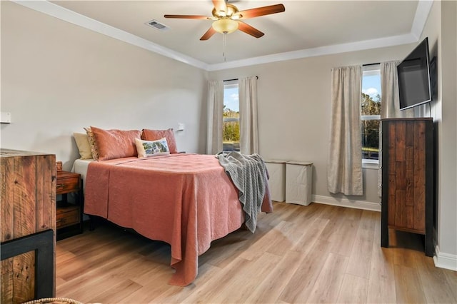 bedroom with light wood finished floors, crown molding, a ceiling fan, visible vents, and baseboards