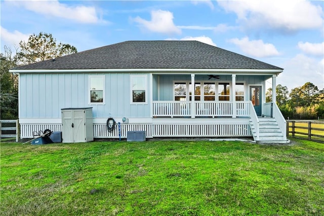 rear view of house with fence, covered porch, a yard, and a shingled roof