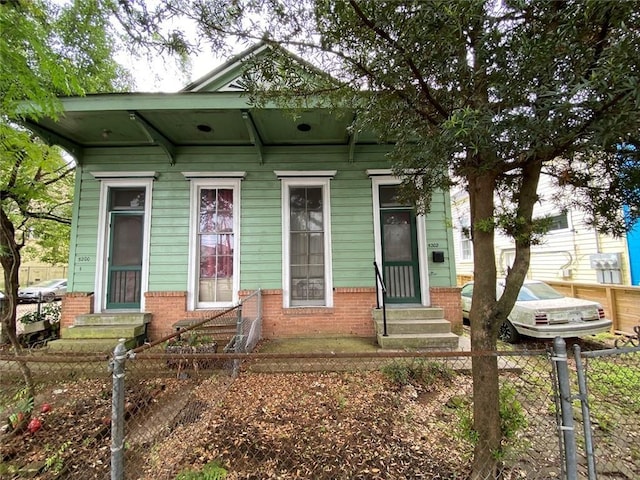 520002 Magazine St, New Orleans, LA 70115 - shotgun-style home featuring entry steps, a fenced front yard, and brick siding