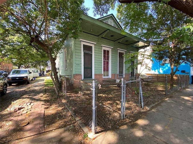 520002 Magazine St, New Orleans, LA 70115 - shotgun-style home with a fenced front yard, brick siding, and a gate