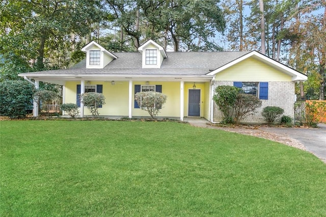 view of front of house with a front lawn, roof with shingles, and covered porch