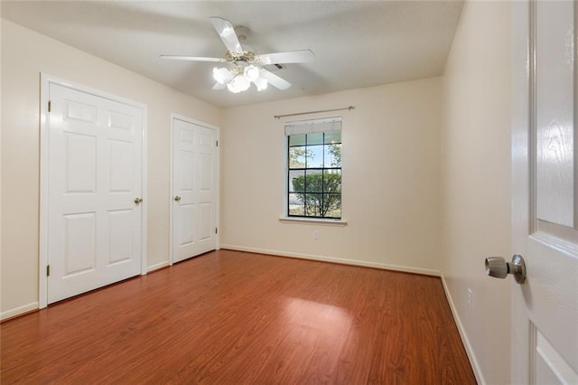 unfurnished bedroom featuring wood finished floors, a ceiling fan, and baseboards