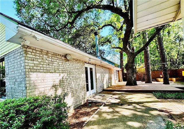 view of home's exterior featuring a wooden deck, fence, and a patio