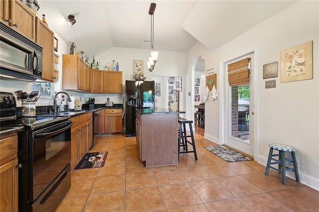 kitchen with black appliances, dark countertops, a breakfast bar, and a kitchen island