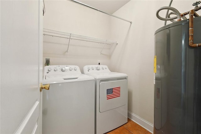 clothes washing area with washing machine and clothes dryer, tile patterned floors, electric water heater, baseboards, and laundry area