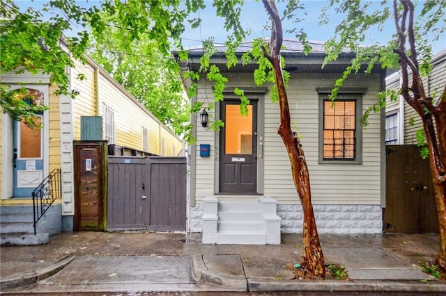 shotgun-style home with entry steps and a gate