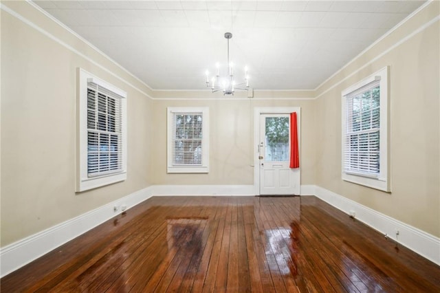 foyer entrance featuring hardwood / wood-style floors, baseboards, a notable chandelier, and ornamental molding
