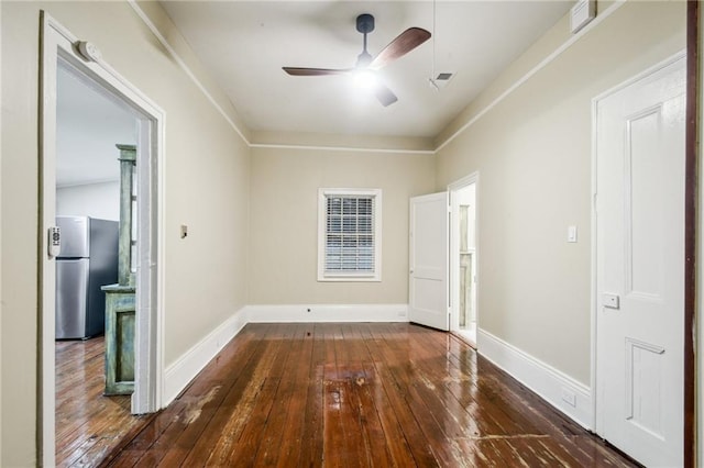 spare room with wood-type flooring, visible vents, baseboards, and ceiling fan