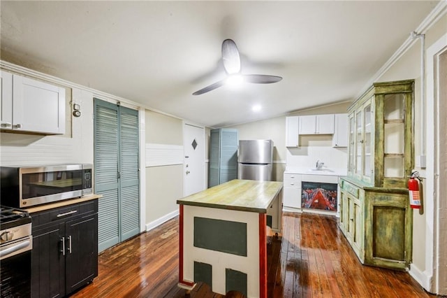 kitchen featuring a ceiling fan, a sink, stainless steel appliances, white cabinets, and dark wood-type flooring