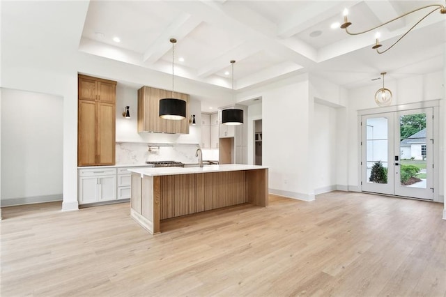 kitchen with light countertops, beamed ceiling, baseboards, light wood-style flooring, and tasteful backsplash