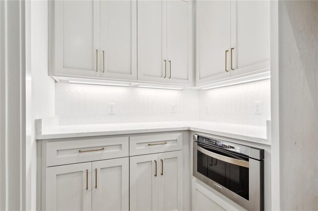 kitchen with white cabinets, wall oven, and light countertops