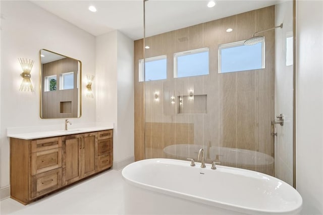 full bath featuring vanity, a tile shower, a freestanding tub, and recessed lighting