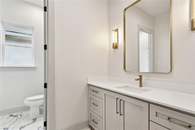 bathroom with marble finish floor, toilet, vanity, and baseboards