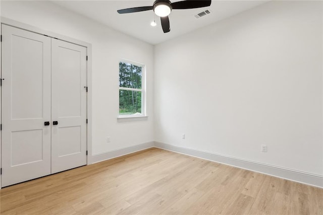 unfurnished bedroom featuring a ceiling fan, a closet, light wood-type flooring, baseboards, and visible vents