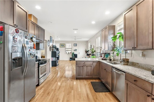 2900 General Taylor St, New Orleans, LA 70115 - kitchen featuring light stone countertops, appliances with stainless steel finishes, light wood-style floors, a ceiling fan, and under cabinet range hood