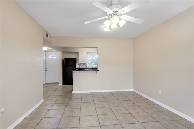 spare room featuring visible vents, baseboards, light tile patterned flooring, and ceiling fan