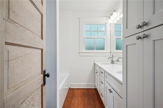 720 Moss St, New Orleans, LA 70119 - bathroom with baseboards, double vanity, and wood finished floors