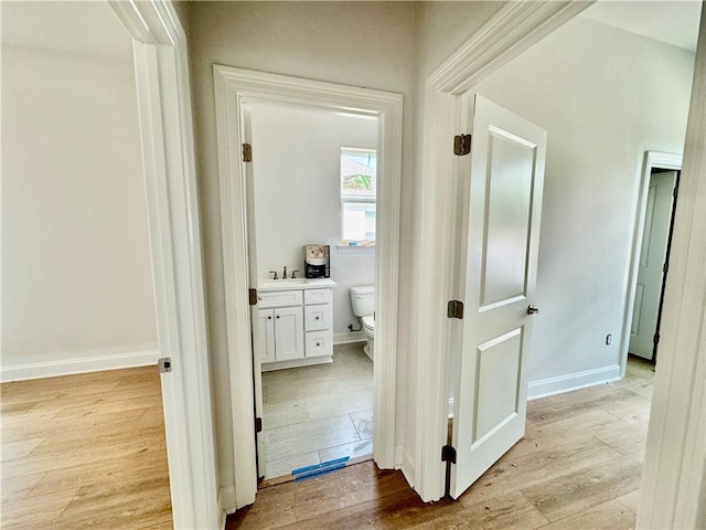 20326 Quincy Ave, Covington, LA 70433 - hallway with a sink, light wood-style floors, and baseboards