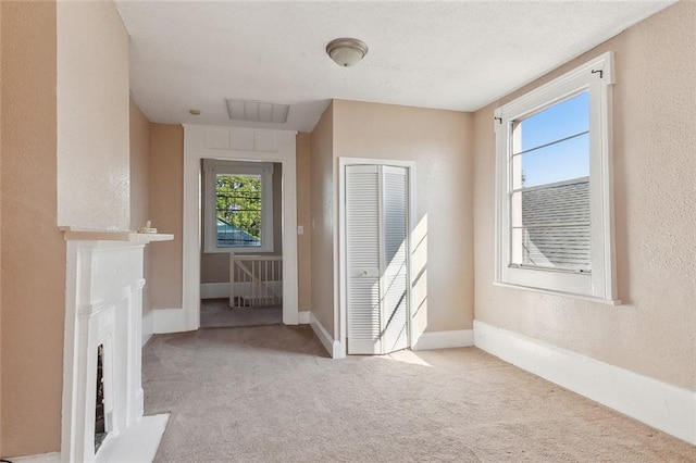 201921 N Rampart St, New Orleans, LA 70116 - carpeted empty room featuring baseboards, a textured wall, and a fireplace