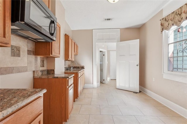 201921 N Rampart St, New Orleans, LA 70116 - kitchen with baseboards, dark stone counters, a sink, and light tile patterned floors