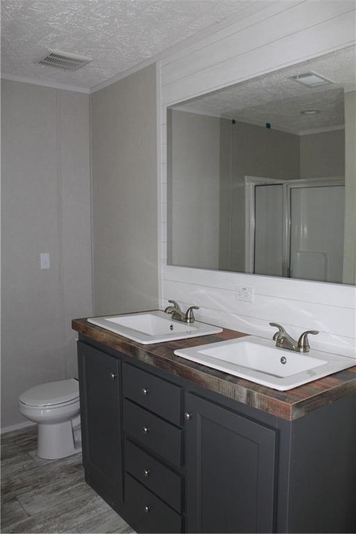 full bathroom with visible vents, wood finished floors, a sink, and a textured ceiling