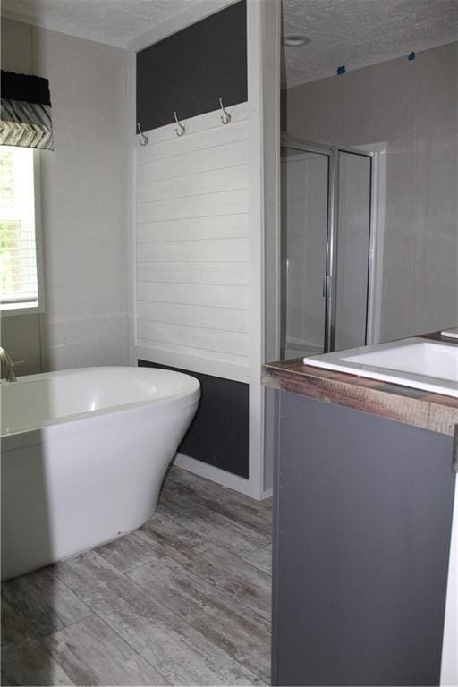 full bathroom featuring a freestanding tub, wood finished floors, a textured ceiling, and a stall shower