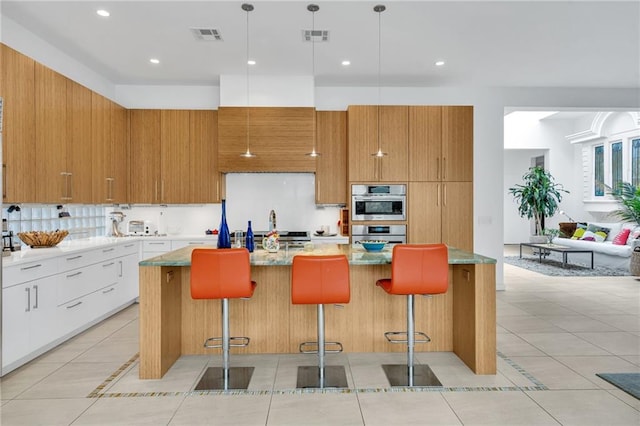 1704 Milan St, New Orleans, LA 70115 - kitchen with a kitchen island with sink, stainless steel double oven, modern cabinets, and visible vents
