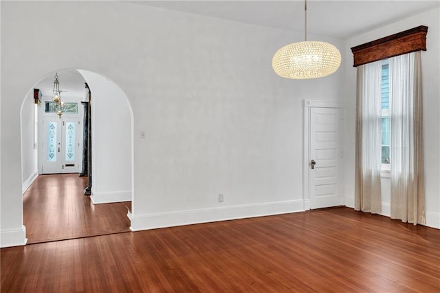 1704 Milan St, New Orleans, LA 70115 - unfurnished dining area featuring a chandelier, baseboards, arched walkways, and wood finished floors
