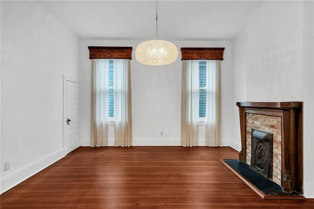1704 Milan St, New Orleans, LA 70115 - unfurnished living room with a brick fireplace, an inviting chandelier, wood finished floors, and plenty of natural light