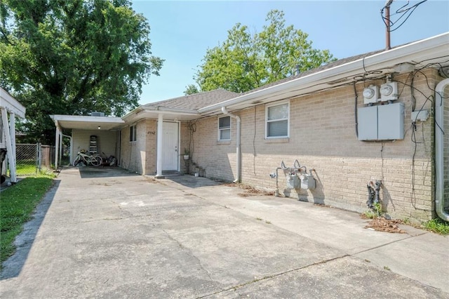 view of front of home with fence, driveway, brick siding, and an attached carport
