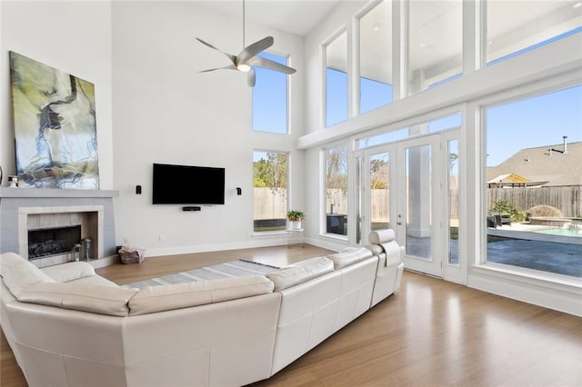 544 Belle Pointe Loop, Madisonville, LA 70447 - living area with a ceiling fan, wood finished floors, a high ceiling, a tiled fireplace, and baseboards