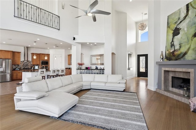 544 Belle Pointe Loop, Madisonville, LA 70447 - living room with baseboards, a fireplace with raised hearth, a ceiling fan, wood finished floors, and a high ceiling