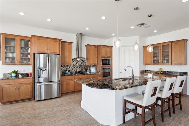 544 Belle Pointe Loop, Madisonville, LA 70447 - kitchen featuring wall chimney exhaust hood, a sink, visible vents, brown cabinets, and appliances with stainless steel finishes