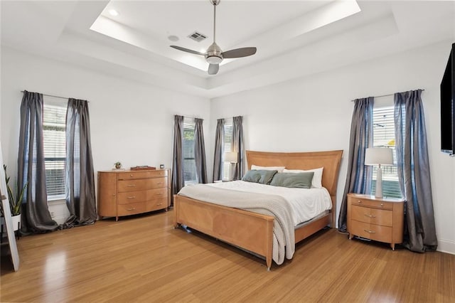 544 Belle Pointe Loop, Madisonville, LA 70447 - bedroom featuring ceiling fan, a tray ceiling, visible vents, and light wood-type flooring