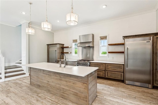 640 Bocage Ct N, Covington, LA 70433 - kitchen featuring premium appliances, open shelves, wall chimney exhaust hood, crown molding, and light wood finished floors
