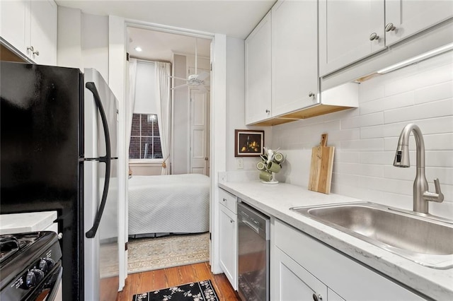 931 Chartres Street 13&14, New Orleans, LA 70116 - kitchen with white cabinets, stainless steel dishwasher, a sink, freestanding refrigerator, and light countertops