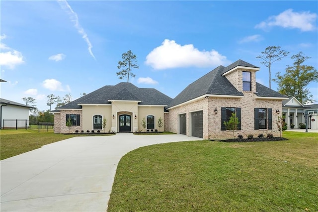 french country style house with fence, concrete driveway, a front yard, and french doors