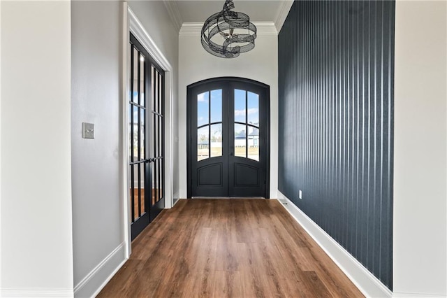 doorway to outside with crown molding, baseboards, arched walkways, french doors, and wood finished floors