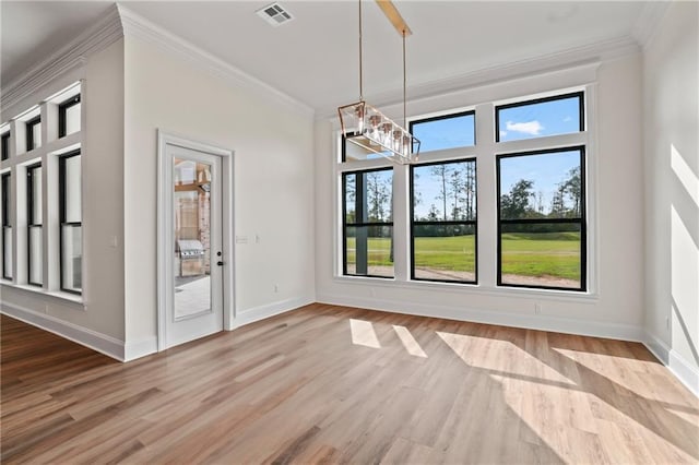 unfurnished dining area featuring a chandelier, baseboards, wood finished floors, and crown molding