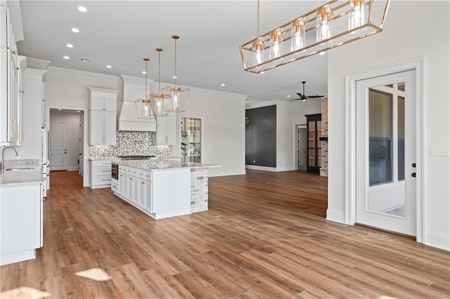 kitchen featuring recessed lighting, a sink, custom exhaust hood, ornamental molding, and open floor plan