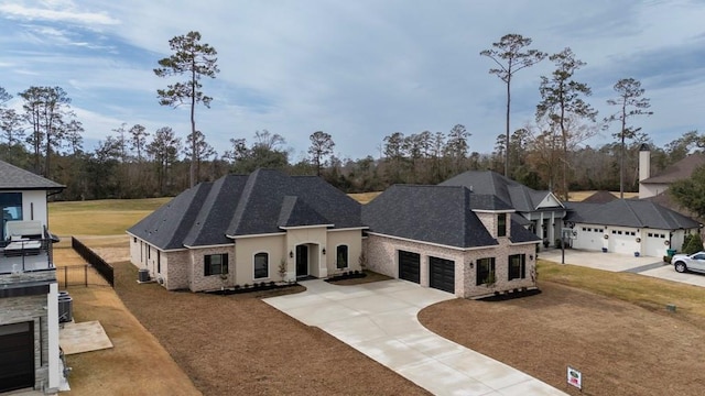 french country style house with a front lawn, driveway, an attached garage, and roof with shingles