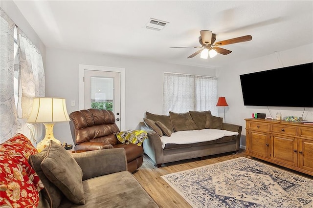 living room featuring visible vents, light wood finished floors, and ceiling fan