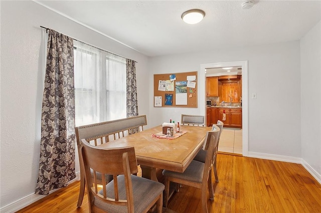 dining area featuring light wood finished floors and baseboards