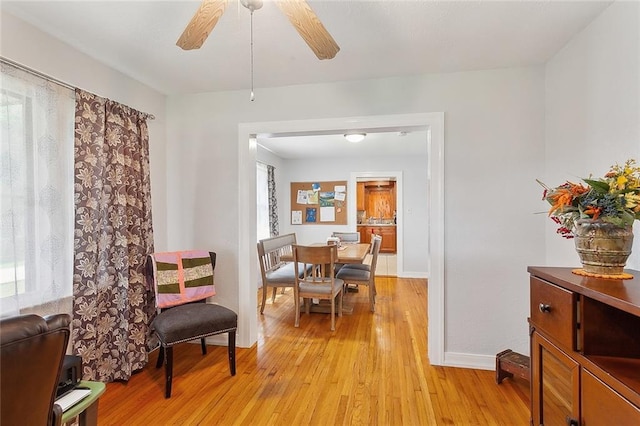 living area featuring baseboards, a ceiling fan, and light wood-style flooring