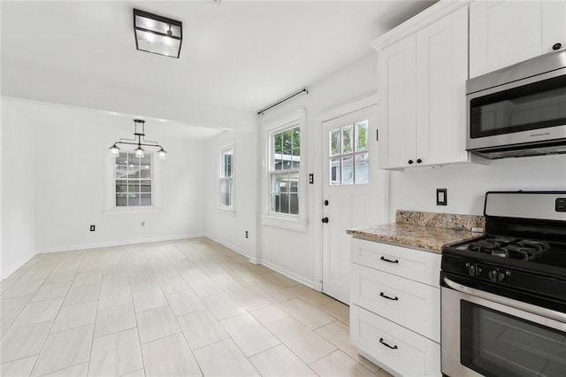 kitchen featuring white cabinets, stainless steel appliances, baseboards, and light stone counters