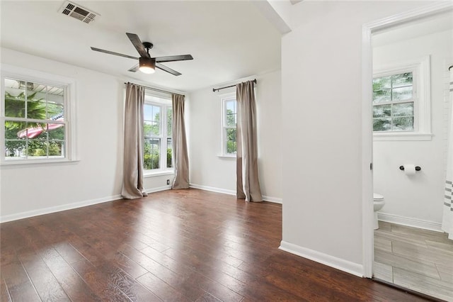 spare room featuring baseboards, visible vents, ceiling fan, and dark wood finished floors