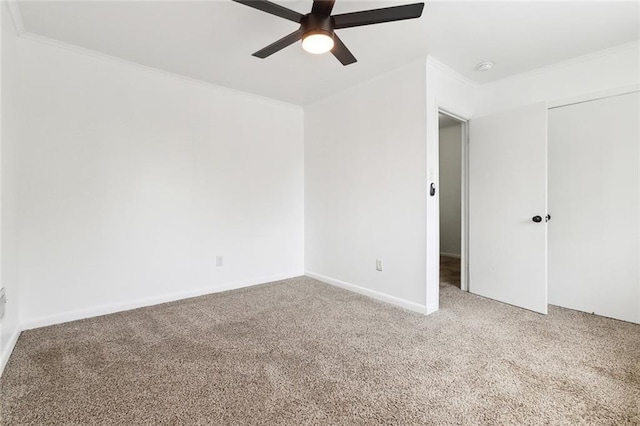 carpeted spare room with ornamental molding, baseboards, and a ceiling fan